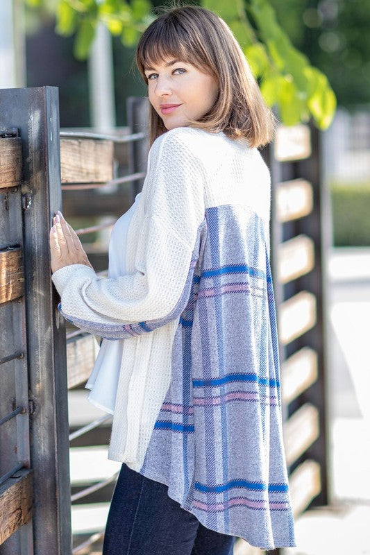 A woman models the Plaid Back Waffle Knit Cardigan paired with black pants, standing against a light background.