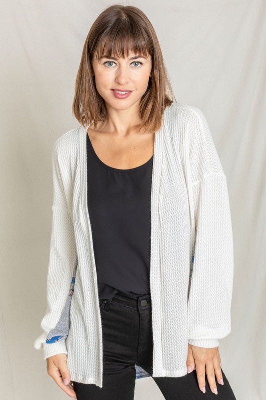 A woman models the Plaid Back Waffle Knit Cardigan paired with black pants, standing against a light background.