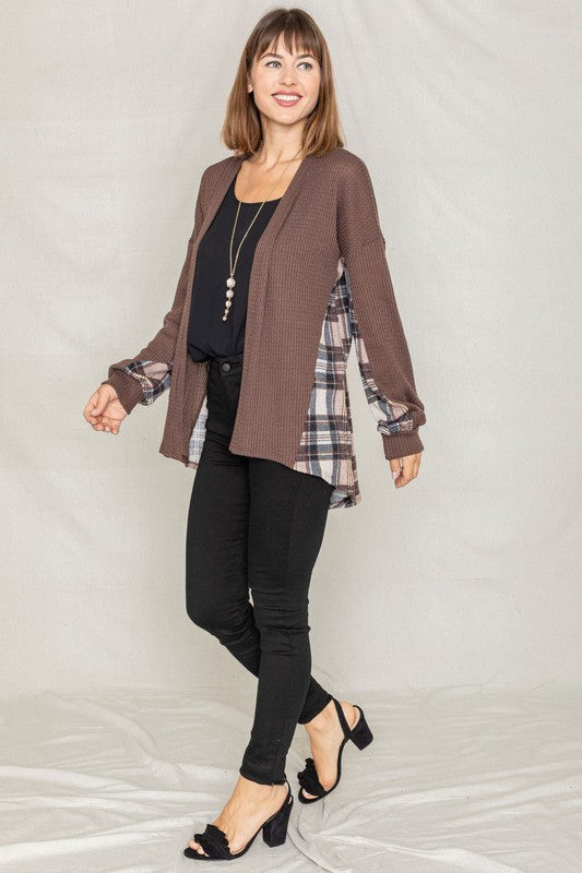 A woman models the Plaid Back Waffle Knit Cardigan paired with black pants, standing against a light background.