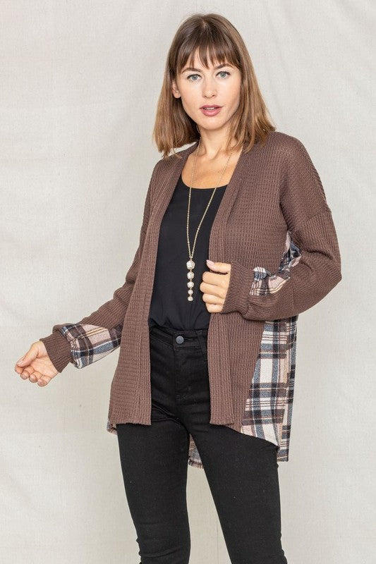 A woman models the Plaid Back Waffle Knit Cardigan paired with black pants, standing against a light background.