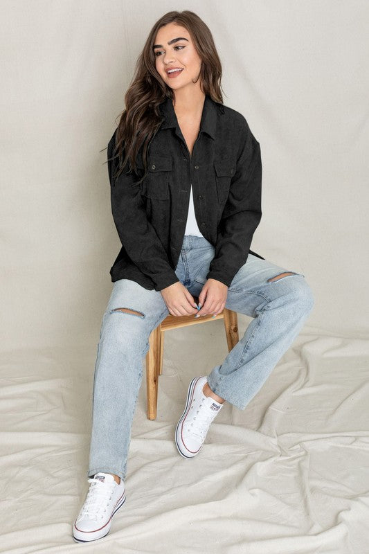 A woman in a light gray Corduroy Boyfriend Oversize Jacket, made in China, stands against a neutral backdrop wearing it over a white top and dark jeans.