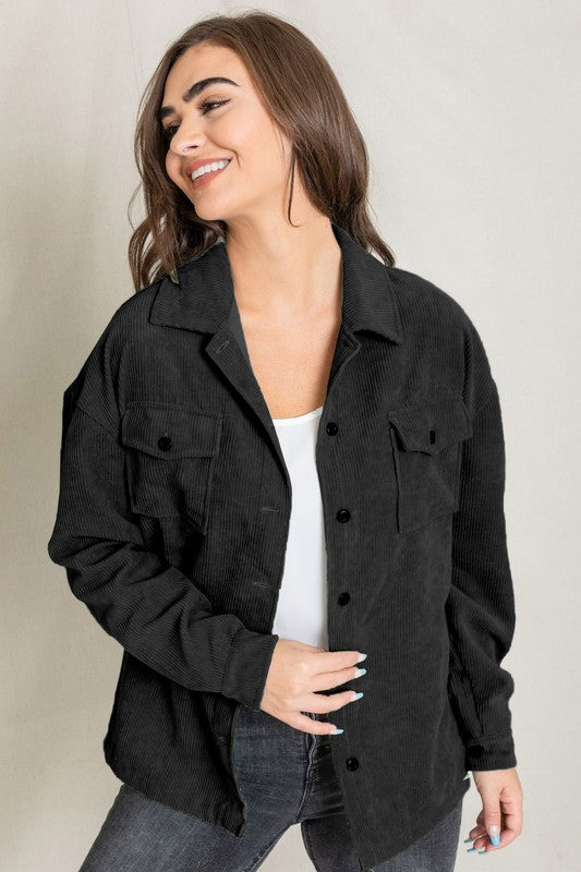 A woman in a light gray Corduroy Boyfriend Oversize Jacket, made in China, stands against a neutral backdrop wearing it over a white top and dark jeans.