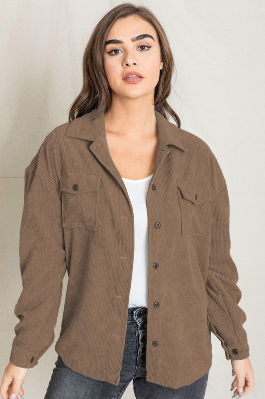 A woman in a light gray Corduroy Boyfriend Oversize Jacket, made in China, stands against a neutral backdrop wearing it over a white top and dark jeans.