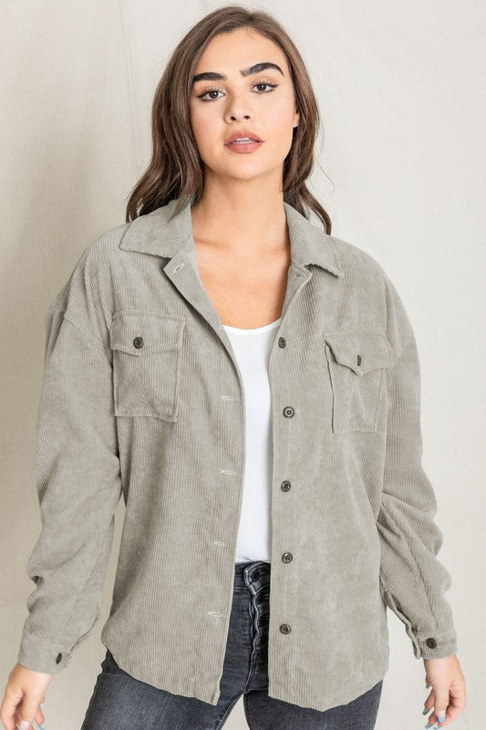 A woman in a light gray Corduroy Boyfriend Oversize Jacket, made in China, stands against a neutral backdrop wearing it over a white top and dark jeans.