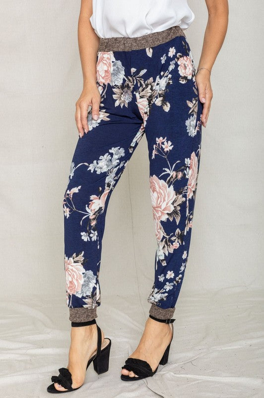 Modeling the Rose Print Jogger, this ensemble highlights a soft polyester and spandex blend with a sleek gray waistband and cuffs, perfectly paired with black heeled sandals to enhance elegance.