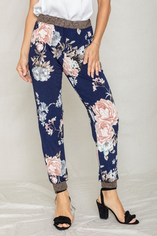 Modeling the Rose Print Jogger, this ensemble highlights a soft polyester and spandex blend with a sleek gray waistband and cuffs, perfectly paired with black heeled sandals to enhance elegance.