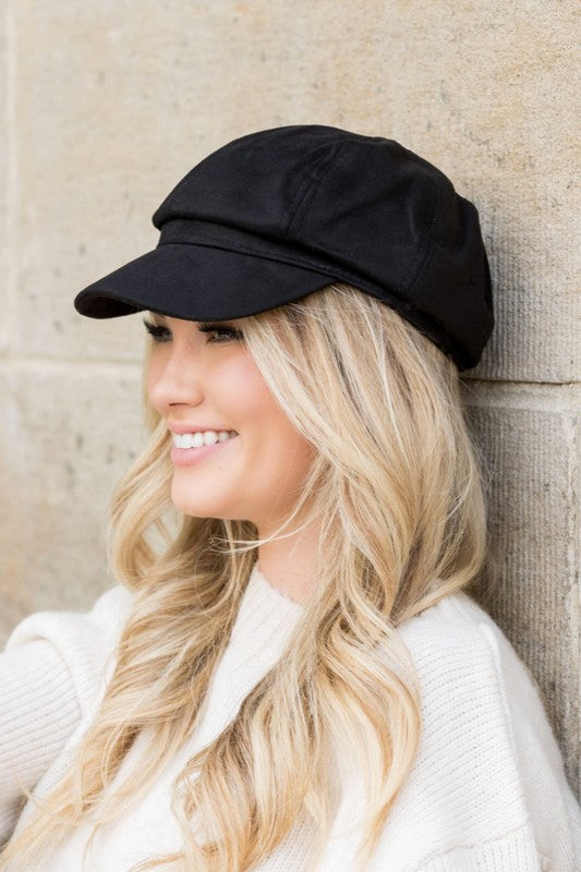 Woman smiling while tipping her adjustable Suede Newsboy Cap forward.
