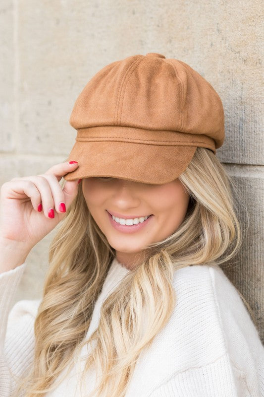 Woman smiling while tipping her adjustable Suede Newsboy Cap forward.