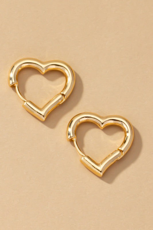 Two Heart Shape Hinged Huggie Hoop Earrings, adorned in gold plating, are displayed on a beige surface.