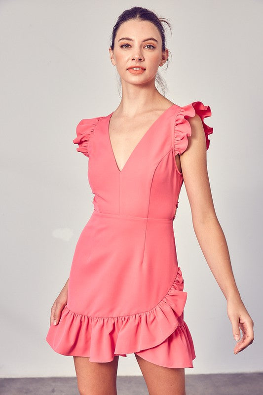 A person wearing the elegant, sleeveless V-Neck Ruffle Dress in chic pink, complete with ruffled shoulders and hem, stands against a plain background—an effortlessly versatile wardrobe staple.