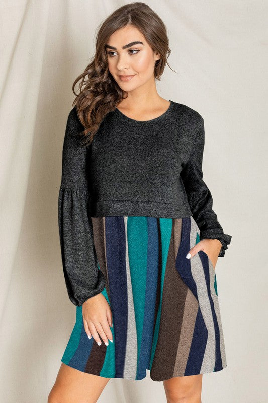 A woman is standing in front of a light-colored backdrop, wearing the Balloon Sleeve Pullover Dress, which features vertical multicolored stripes and convenient skirt pockets.