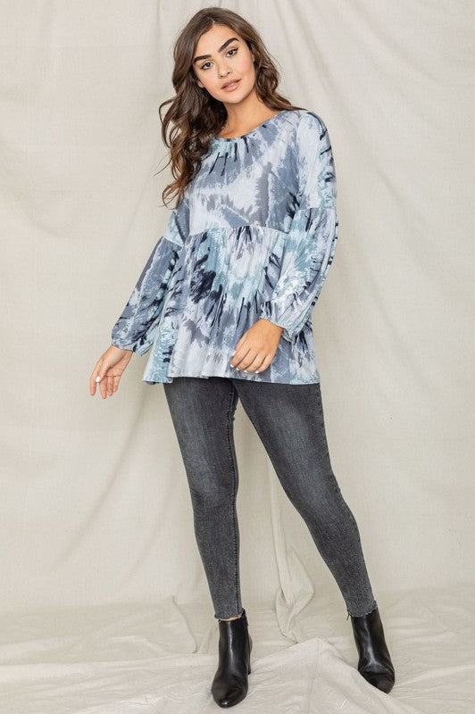 A woman with long brown hair is smiling and looking down while wearing a Swirl Tie Dye Bishop Sleeve Tunic.