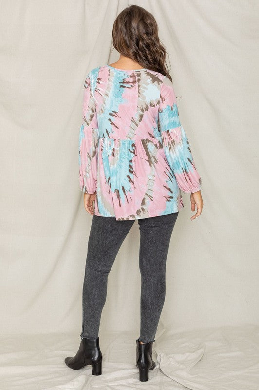 A woman with long brown hair is smiling and looking down while wearing a Swirl Tie Dye Bishop Sleeve Tunic.