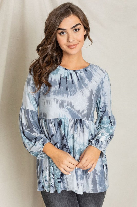 A woman with long brown hair is smiling and looking down while wearing a Swirl Tie Dye Bishop Sleeve Tunic.