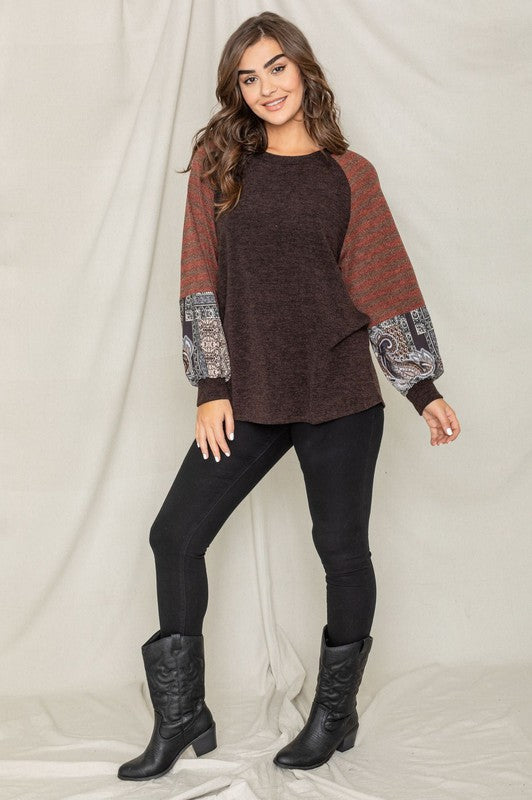 A woman wearing the Terry Stripe Bishop Sleeve Tunic in brown stands against a plain backdrop, looking to her right.