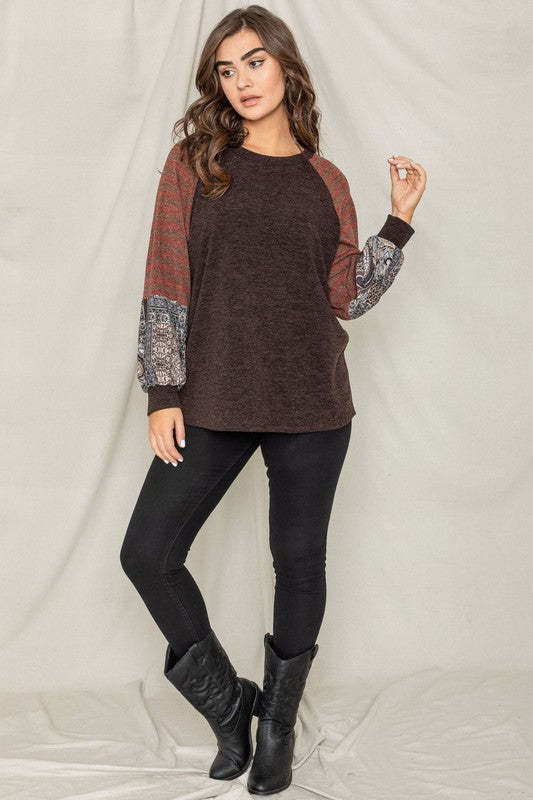 A woman wearing the Terry Stripe Bishop Sleeve Tunic in brown stands against a plain backdrop, looking to her right.