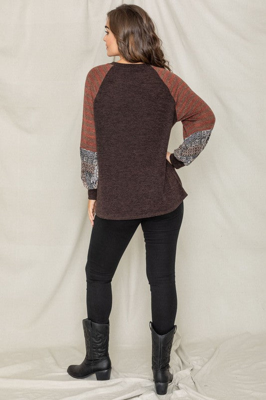 A woman wearing the Terry Stripe Bishop Sleeve Tunic in brown stands against a plain backdrop, looking to her right.