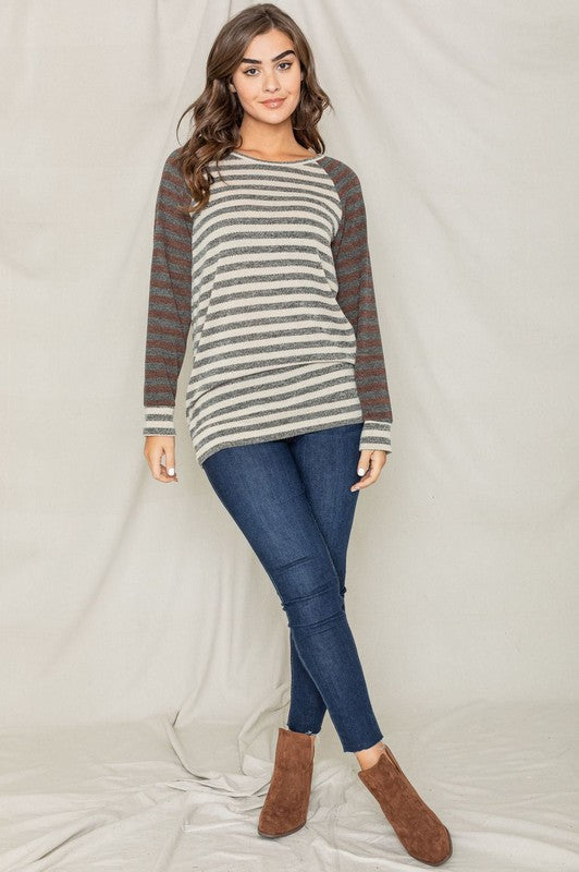 A woman wearing a Two Tone Terry Stripe Tunic with red sleeves and made from a blend of Polyester, Rayon, and Spandex looks off to the side.