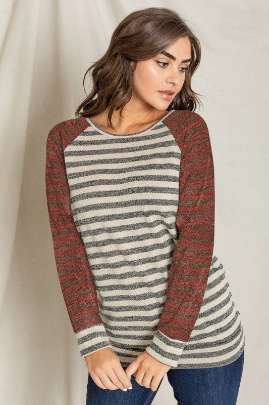 A woman wearing a Two Tone Terry Stripe Tunic with red sleeves and made from a blend of Polyester, Rayon, and Spandex looks off to the side.