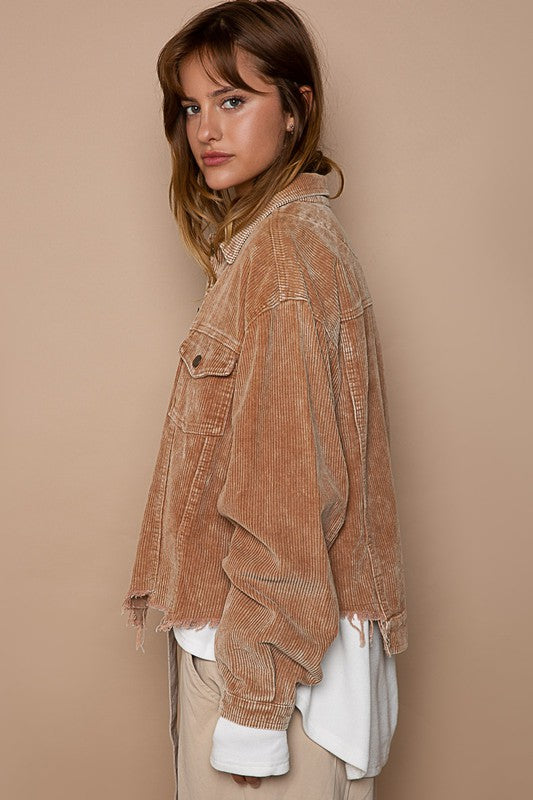 Woman wearing an oversized ribbed shacket with long sleeves and front pockets, exuding cozy comfort against a plain background.