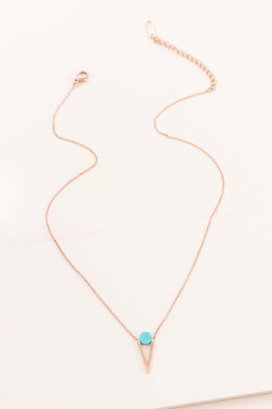 Three Tensly Point Stone Necklaces in rose gold boast a triangular charm pendant, each embellished with a natural stone available in white, turquoise, or black, elegantly displayed side by side.