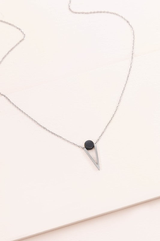 The Tensly Point Stone Necklace Silver collection features three charm necklaces with silver chains, each showcasing a triangular pendant enhanced by a circular accent in black, turquoise, and white. Displayed on a light background, these stainless steel pieces elegantly emphasize the allure of natural stones.