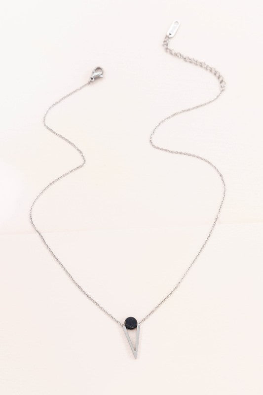 The Tensly Point Stone Necklace Silver collection features three charm necklaces with silver chains, each showcasing a triangular pendant enhanced by a circular accent in black, turquoise, and white. Displayed on a light background, these stainless steel pieces elegantly emphasize the allure of natural stones.