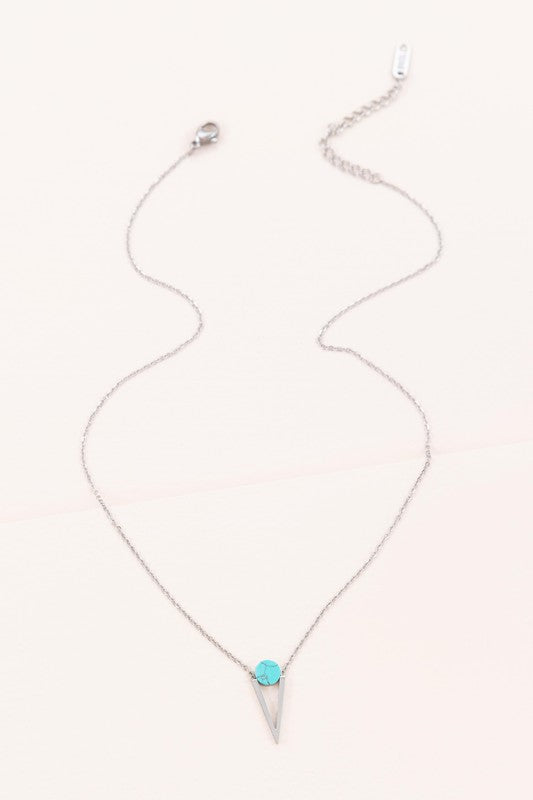 The Tensly Point Stone Necklace Silver collection features three charm necklaces with silver chains, each showcasing a triangular pendant enhanced by a circular accent in black, turquoise, and white. Displayed on a light background, these stainless steel pieces elegantly emphasize the allure of natural stones.