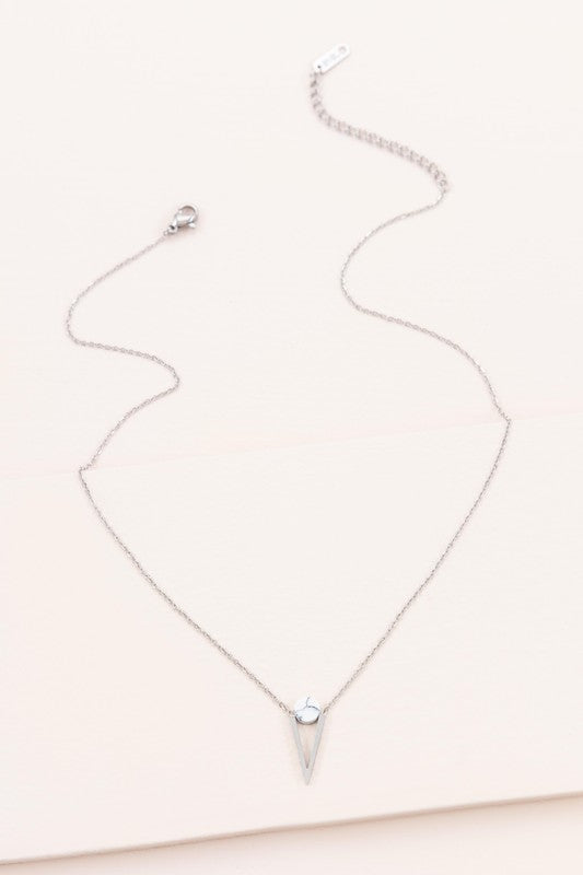 The Tensly Point Stone Necklace Silver collection features three charm necklaces with silver chains, each showcasing a triangular pendant enhanced by a circular accent in black, turquoise, and white. Displayed on a light background, these stainless steel pieces elegantly emphasize the allure of natural stones.