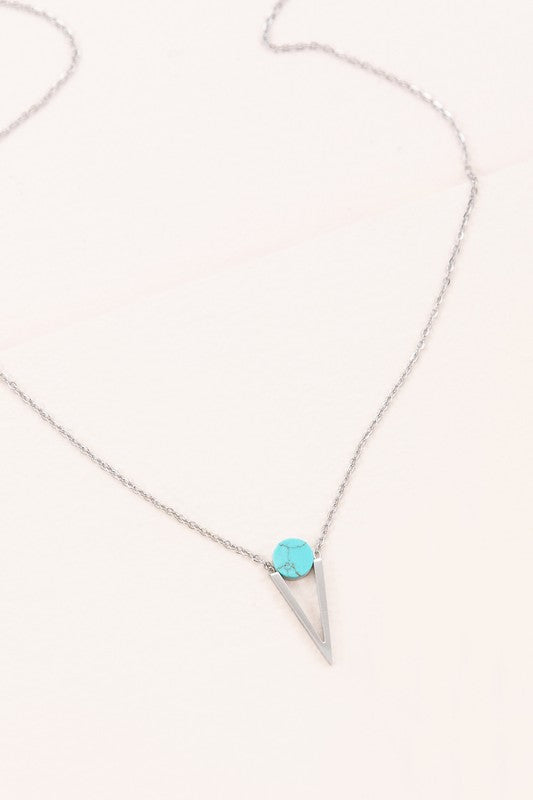 The Tensly Point Stone Necklace Silver collection features three charm necklaces with silver chains, each showcasing a triangular pendant enhanced by a circular accent in black, turquoise, and white. Displayed on a light background, these stainless steel pieces elegantly emphasize the allure of natural stones.