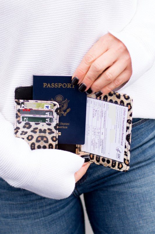 Person holding the Passport and Vaccine Credit Card Wallet made from stylish vegan leather with a leopard print, containing a passport, boarding pass, vaccine card holder, and several cards.