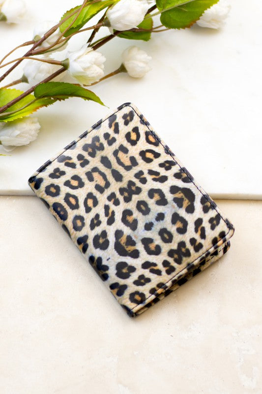 Person holding the Passport and Vaccine Credit Card Wallet made from stylish vegan leather with a leopard print, containing a passport, boarding pass, vaccine card holder, and several cards.