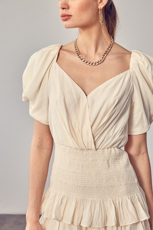 A woman wearing the Puff Sleeves Ruffle Dress in cream stands against a plain background, exuding vintage-inspired elegance.