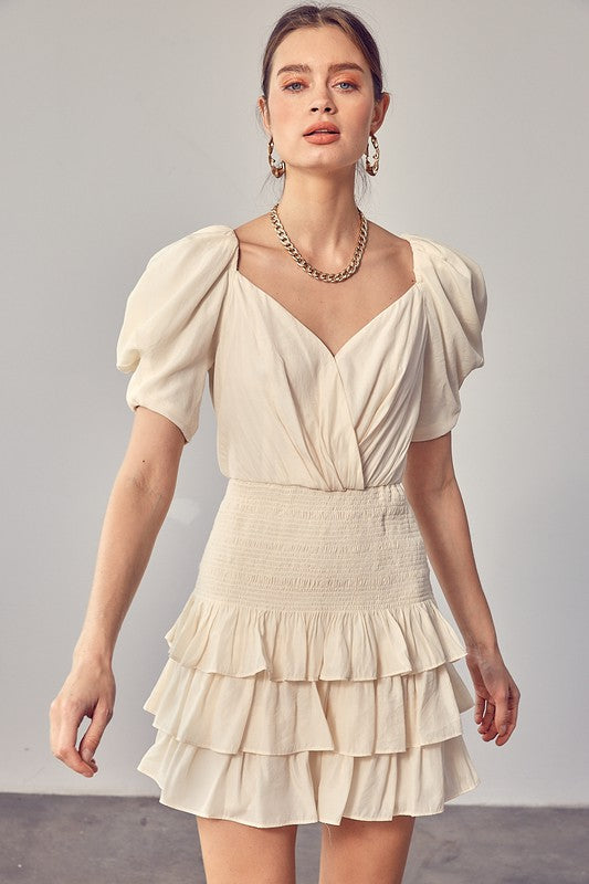 A woman wearing the Puff Sleeves Ruffle Dress in cream stands against a plain background, exuding vintage-inspired elegance.