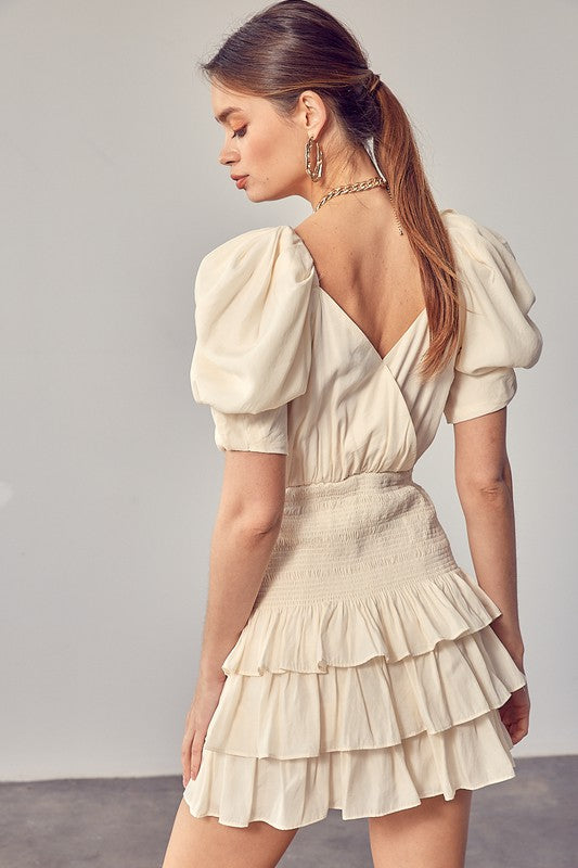 A woman wearing the Puff Sleeves Ruffle Dress in cream stands against a plain background, exuding vintage-inspired elegance.