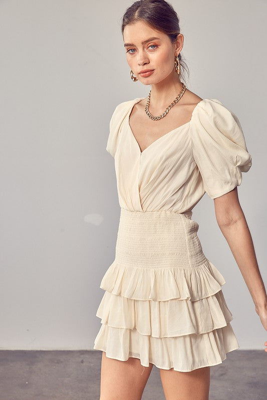 A woman wearing the Puff Sleeves Ruffle Dress in cream stands against a plain background, exuding vintage-inspired elegance.