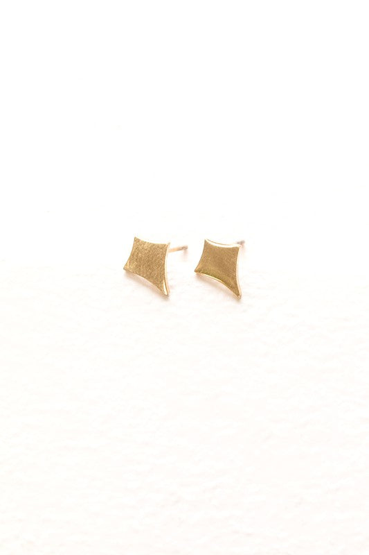 The Sparks Stud Earrings are charming, small diamond-shaped pieces crafted from 14k gold plated material. They are hypoallergenic and stand out beautifully against a white background.