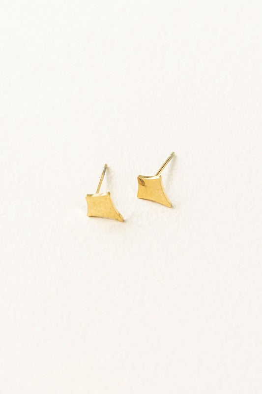 The Sparks Stud Earrings are charming, small diamond-shaped pieces crafted from 14k gold plated material. They are hypoallergenic and stand out beautifully against a white background.