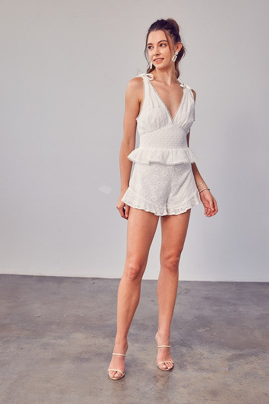 Person wearing Embroidery Eyelet Shorts featuring a white lace design with a floral pattern and ruffled hem, making it a stylish addition to any summer wardrobe.