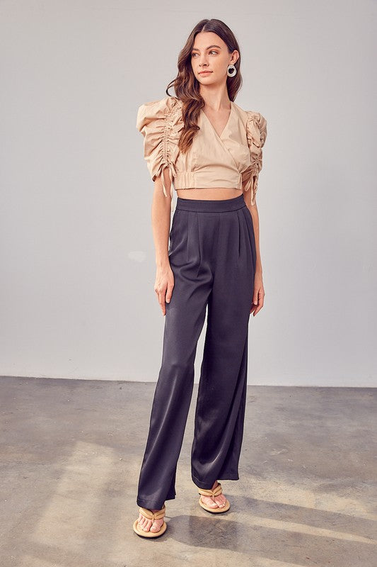 A person wearing Wide Leg Pants and sandals stands on a concrete floor, showcasing a versatile wardrobe with their flowing silhouette.