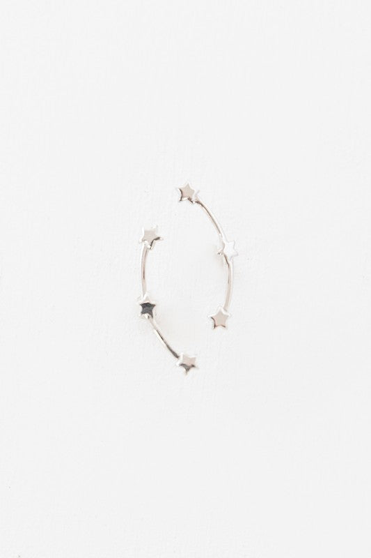 The Starry Crawler earrings, crafted from sterling silver and featuring a crescent shape adorned with small star accents, rest against a white background.