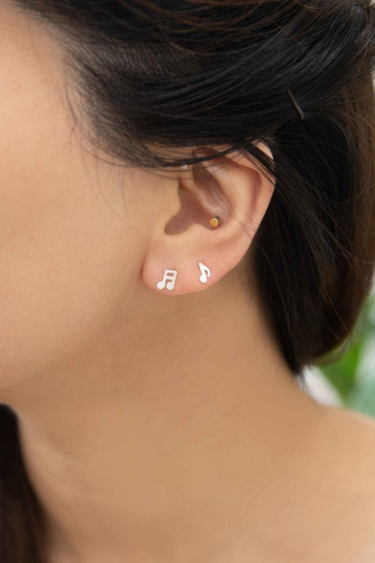 The Musical Note Earrings, crafted from sterling silver and shaped like musical notes, are set against a white background. These asymmetrical earrings are an ideal choice for music enthusiasts wanting to infuse their style with a hint of melody.