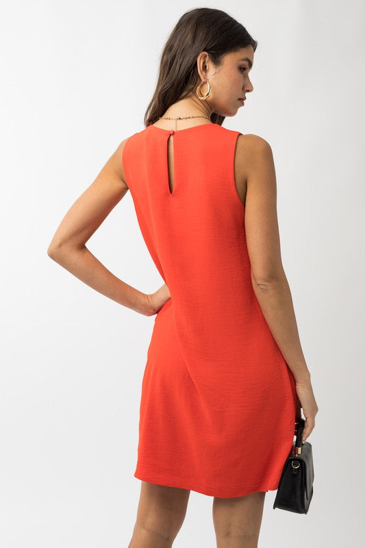 A woman elegantly poses in the Sleeveless V-Neck Dress, highlighting a chic and stylish appearance against a minimalistic backdrop. This versatile wardrobe piece epitomizes both elegance and simplicity.