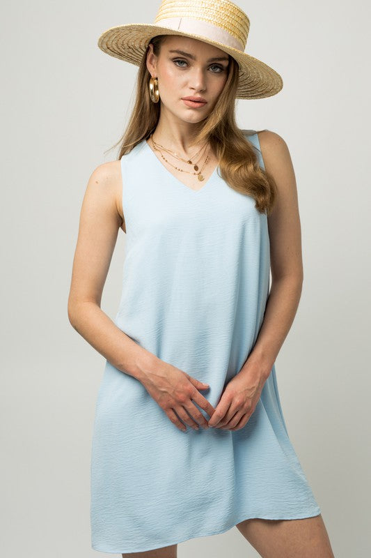 A woman elegantly poses in the Sleeveless V-Neck Dress, highlighting a chic and stylish appearance against a minimalistic backdrop. This versatile wardrobe piece epitomizes both elegance and simplicity.