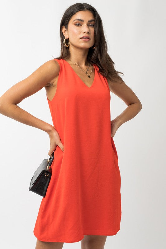 A woman elegantly poses in the Sleeveless V-Neck Dress, highlighting a chic and stylish appearance against a minimalistic backdrop. This versatile wardrobe piece epitomizes both elegance and simplicity.