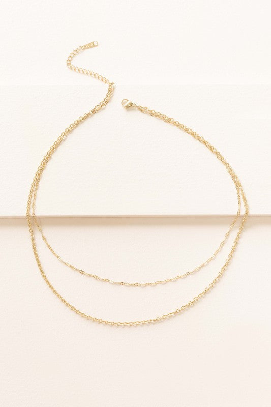 The Othello Layered Necklace is a refined piece crafted from 14k gold-plated stainless steel, featuring a double-layered chain design with a lobster clasp and adjustable length.