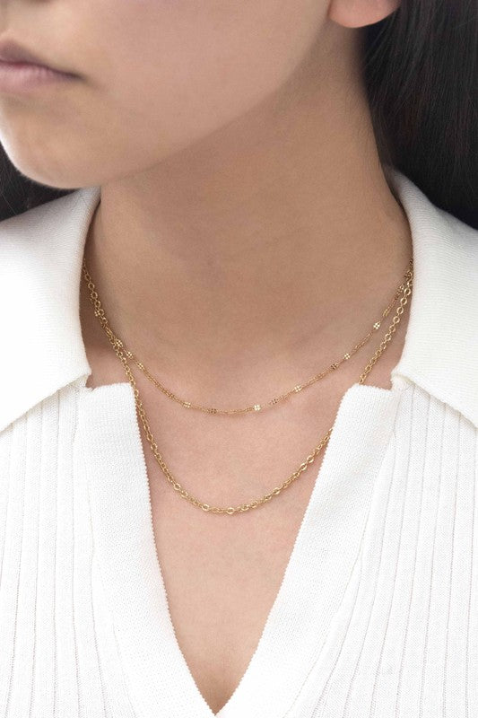 The Othello Layered Necklace is a refined piece crafted from 14k gold-plated stainless steel, featuring a double-layered chain design with a lobster clasp and adjustable length.