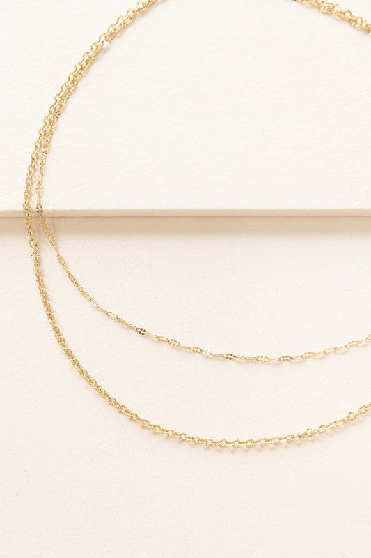 The Othello Layered Necklace is a refined piece crafted from 14k gold-plated stainless steel, featuring a double-layered chain design with a lobster clasp and adjustable length.