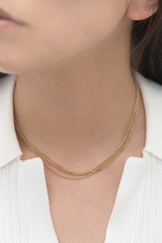 The Juliet Layered Necklace, plated in 14k gold, shines brilliantly against a white background, highlighting the elegance of stainless steel jewelry.