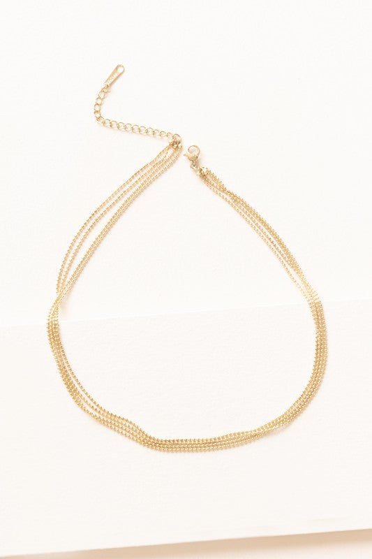 The Juliet Layered Necklace, plated in 14k gold, shines brilliantly against a white background, highlighting the elegance of stainless steel jewelry.